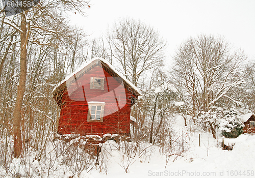 Image of Very old red wooden house in a snowy forest