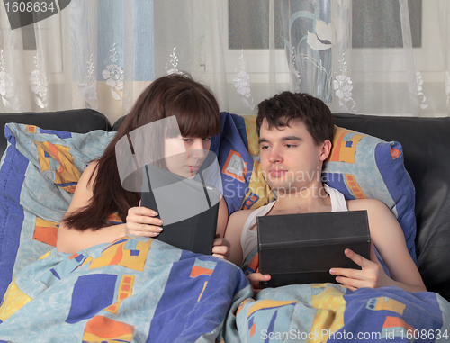 Image of Young couple using tablet PC in their bed