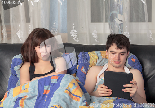 Image of Young couple with tablet PC in their bed