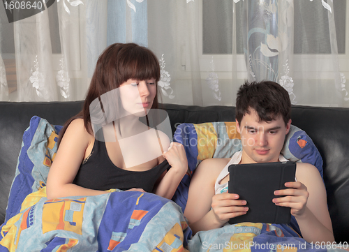 Image of Young couple with tablet PC in their bed