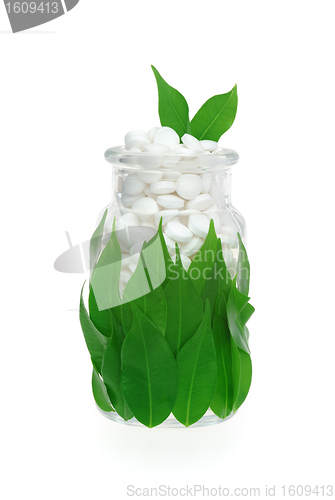 Image of Herbal supplement pills and fresh leaves in glass