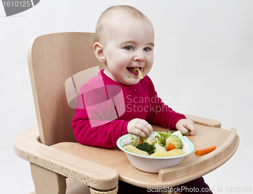 Image of young child eating in high chair