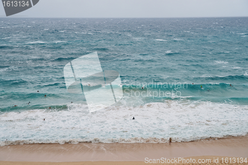 Image of Crowded surfers riding Oahu Island beach waves