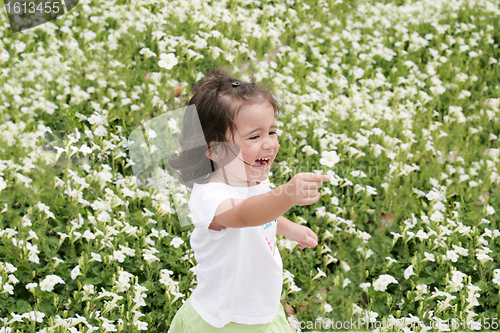 Image of Baby girl happy in a garden of flowers