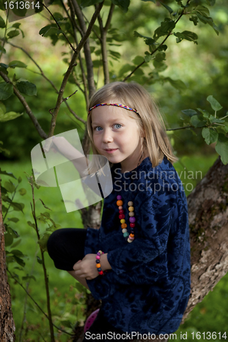 Image of Little girl sitting on a branch of an apple tree