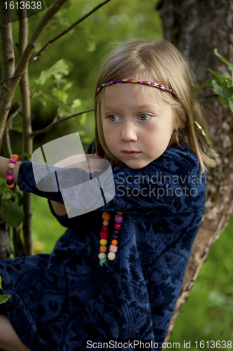 Image of Little girl sitting on a branch of an apple tree
