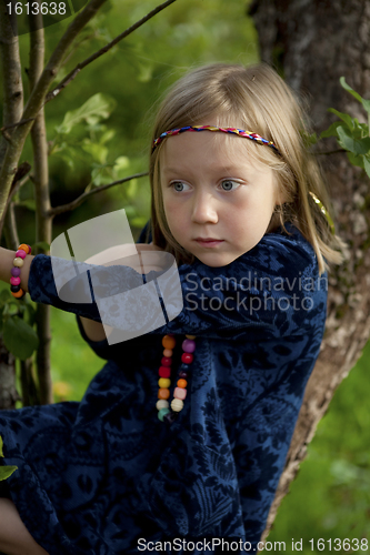 Image of Little girl sitting on a branch of an apple tree