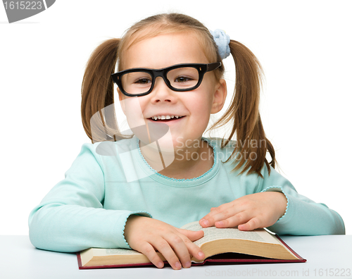 Image of Cute little girl reads a book wearing glasses