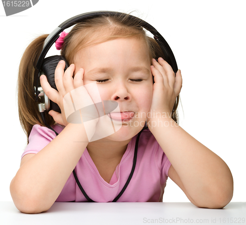 Image of Cute little girl enjoying music using headphones