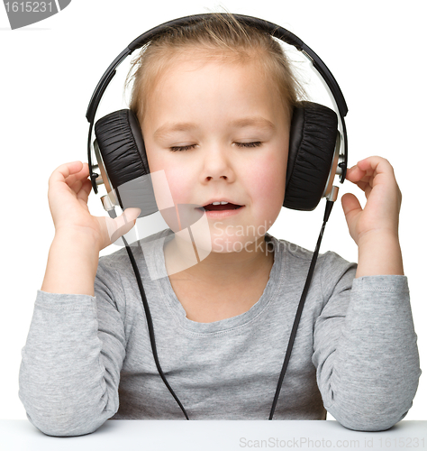 Image of Cute girl enjoying music using headphones