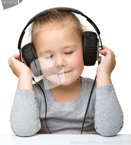 Image of Cute little girl enjoying music using headphones