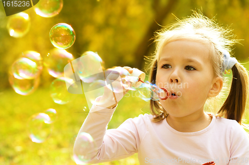 Image of Little girl is blowing a soap bubbles
