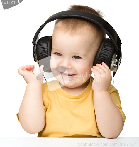 Image of Cute little boy enjoying music using headphones