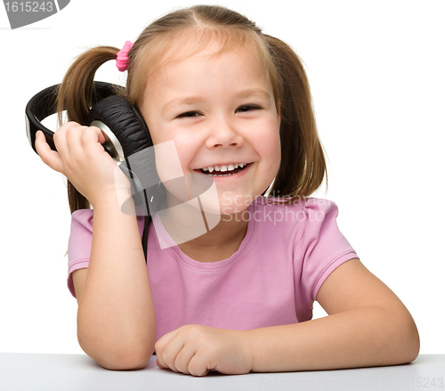 Image of Cute little girl enjoying music using headphones