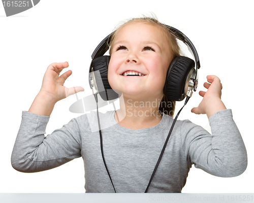 Image of Cute little girl enjoying music using headphones