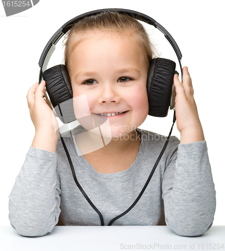 Image of Cute little girl enjoying music using headphones