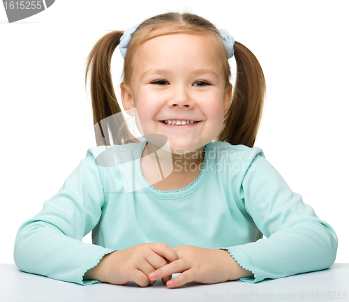 Image of Happy little girl is sitting at the table