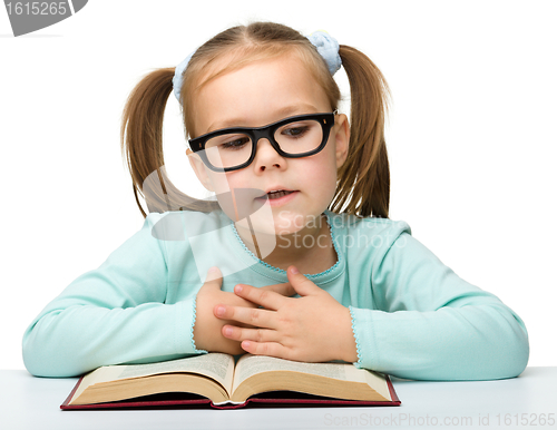 Image of Cute little girl reads a book wearing glasses