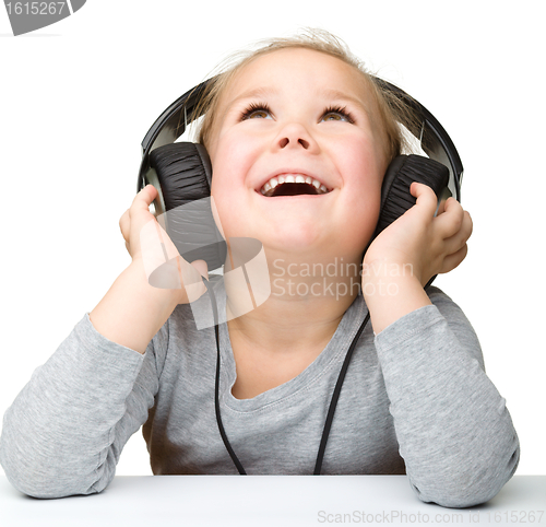 Image of Cute little girl enjoying music using headphones