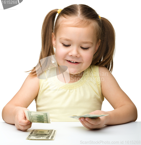 Image of Cute cheerful little girl is counting dollars