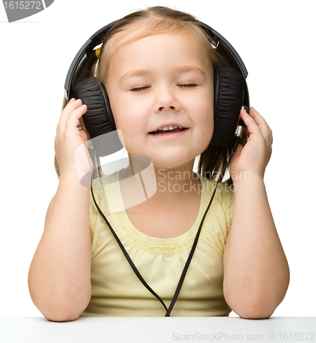 Image of Cute little girl enjoying music using headphones