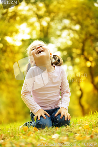 Image of Cute little girl is playing with leaves in park