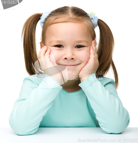 Image of Happy little girl sits at a table and smile