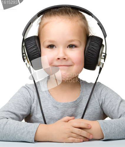 Image of Cute little girl enjoying music using headphones