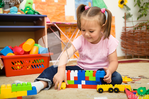 Image of Little girl is playing with building bricks