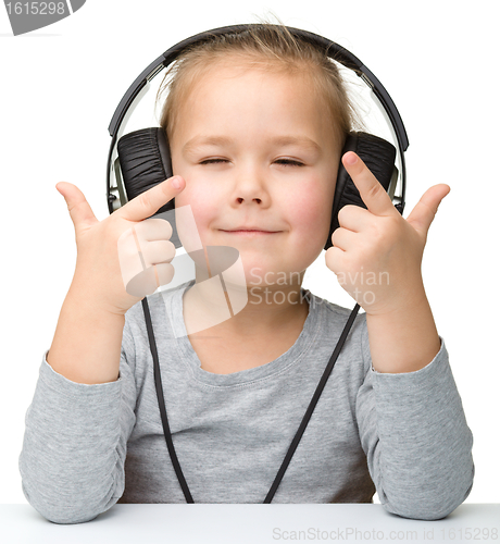 Image of Cute little girl enjoying music using headphones