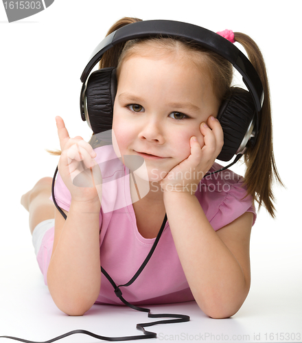 Image of Cute little girl enjoying music using headphones