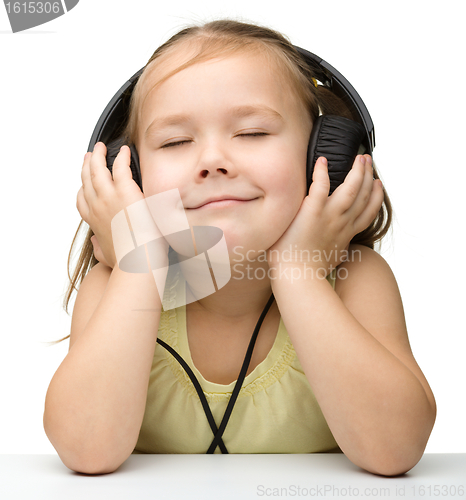 Image of Cute little girl enjoying music using headphones