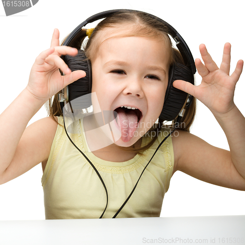Image of Cute little girl enjoying music using headphones