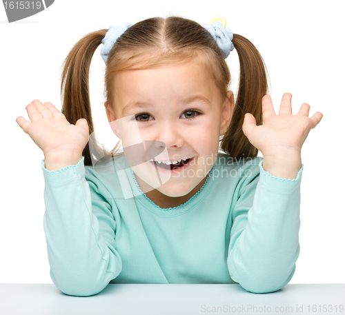 Image of Happy little girl sits at a table and smile