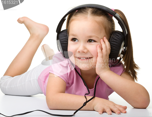 Image of Cute little girl enjoying music using headphones