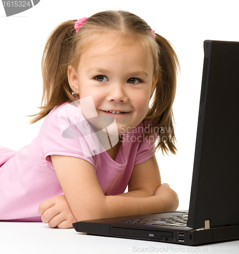 Image of Cute little girl is sitting on floor with laptop