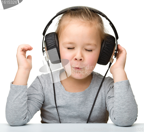 Image of Cute little girl enjoying music using headphones