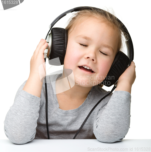 Image of Cute little girl enjoying music using headphones