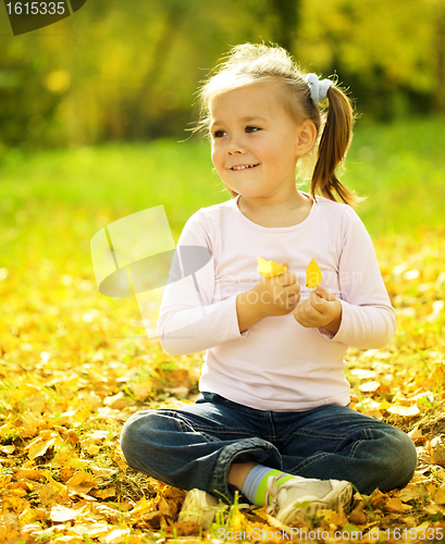 Image of Cute little girl is playing with leaves in park