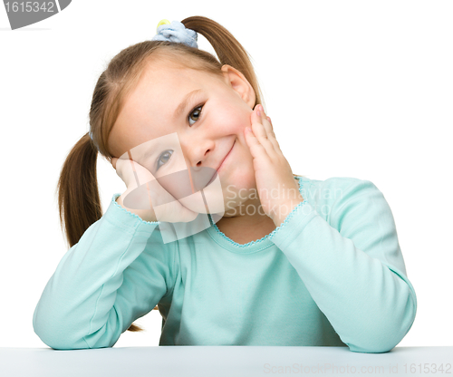 Image of Happy little girl sits at a table and smile