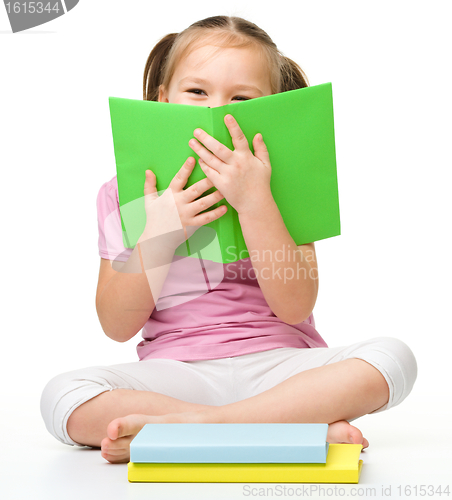 Image of Cute little girl is hiding behind a book