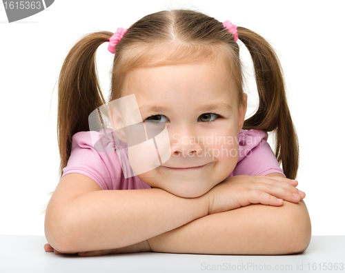 Image of Happy little girl sits at a table and smile