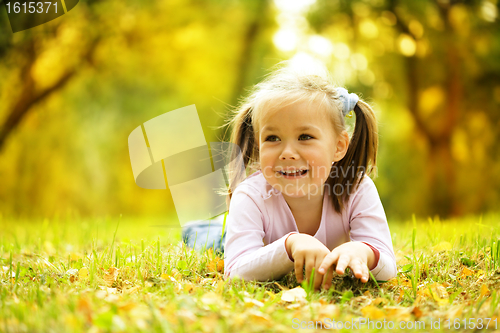 Image of Cute little girl is playing with leaves in park