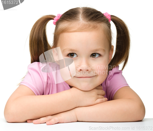 Image of Happy little girl sits at a table and smile