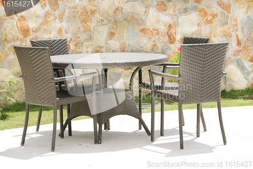Image of Table and chairs in a tropical garden with a stone wall texture