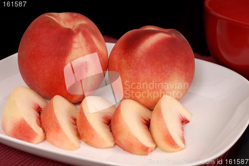 Image of Whole and sliced white peaches on a white plate