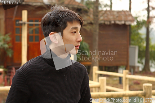 Image of Asian man stand against a old house 