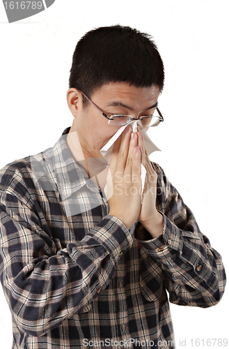 Image of Young man with a cold blowing nose on tissue 