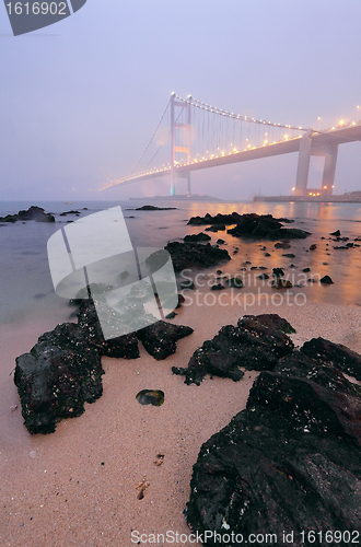 Image of rocks on the beach and bridge in mist