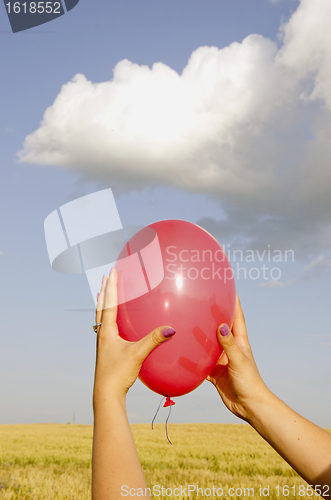 Image of Hand holding red balloon.